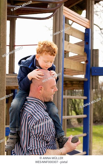 Father carrying son on playground
