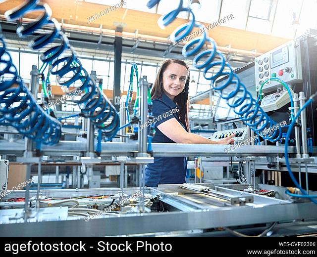 Smiling engineer operating machines at factory