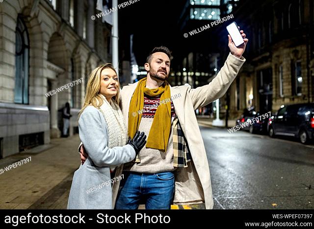 Smiling woman with man hailing for ride on road