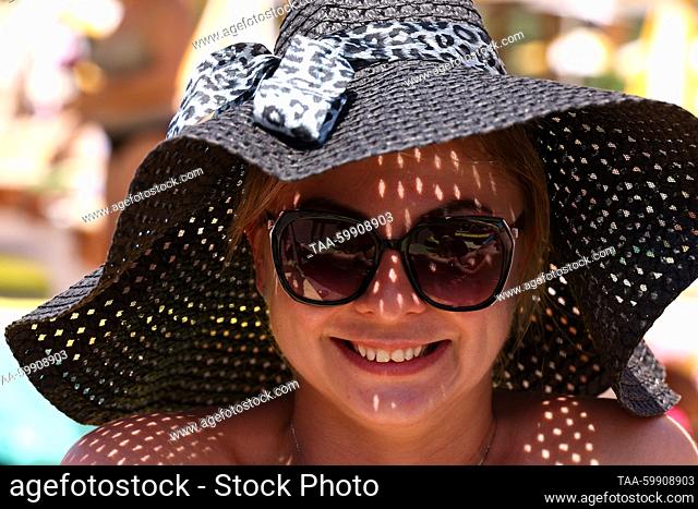 RUSSIA, MOSCOW - JUNE 18, 2023: A woman wearing a hat and sun glasses smiles at the camera at Dream Beach Club in the Dream Island theme park during the summer...