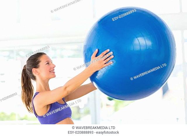 Smiling fit young woman holding fitness ball