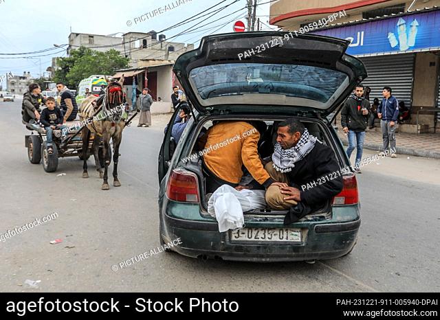 21 December 2023, Palestinian Territories, Rafah: Palestinians transport the body of a relative who was killed by Israeli airstrikes in Rafah