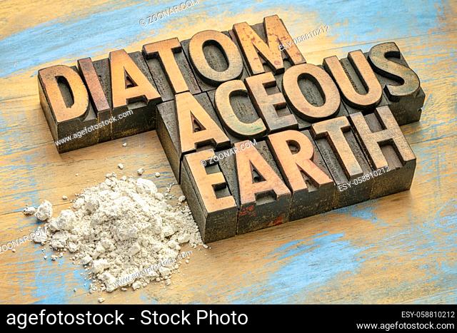 food grade diatomaceous earth supplement - small pile of powder on a grunge wood with a text in vintage letterpress wood type