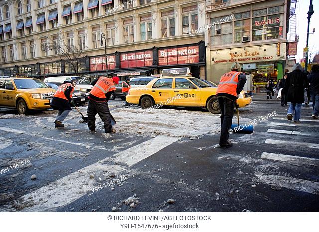Workers hired by the city dig out snow to clear the streets in the Chelsea neighborhood of New York