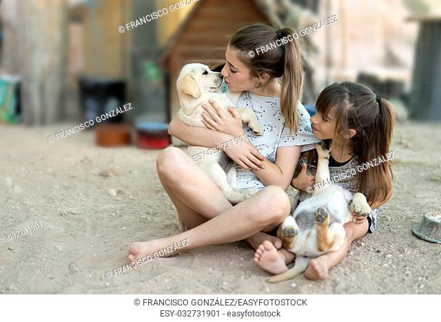 Portrait of two sisters with a golden retriever puppy