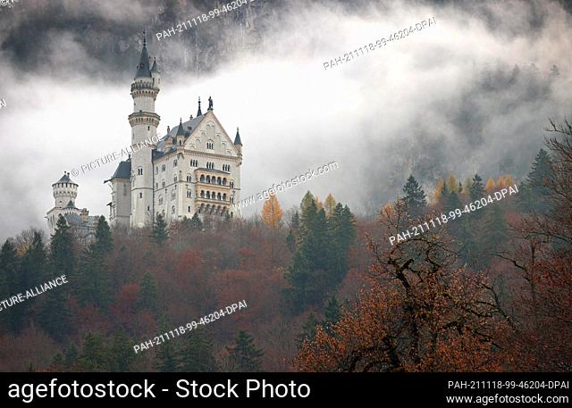 18 November 2021, Bavaria, Schwangau: Neuschwanstein Castle stands shrouded in clouds in the autumnal landscape of the Königswinkel