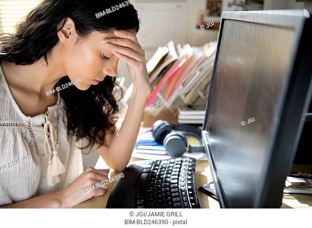 Frustrated Hispanic woman using computer