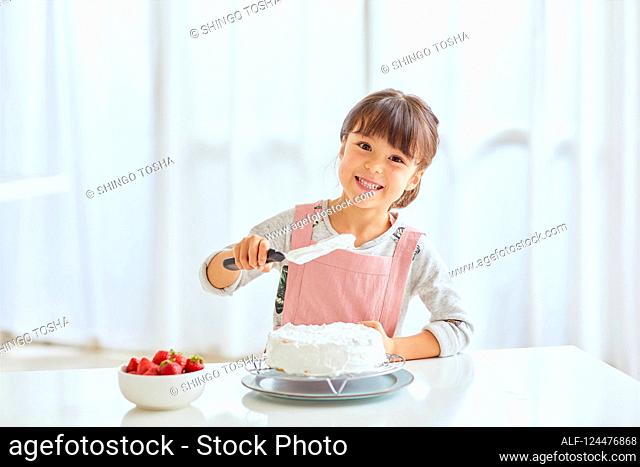 Young happy girl preparing a cake in the kitchen