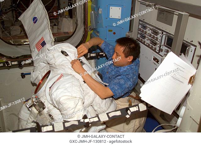 Astronaut Edward T. Lu, Expedition 7 NASA ISS science officer and flight engineer, performs routine maintenance on an Extravehicular Mobility Unit (EMU) space...