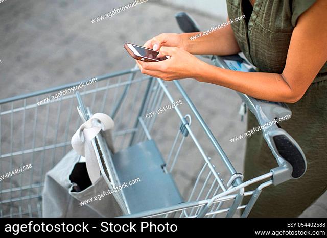 Pretty, young woman going grocery shopping with a trolley