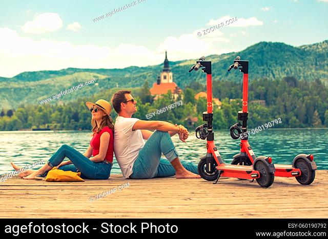 Young couple using electric scooter as modern ecological mean of transport while exploring green country Slovenia at vacations