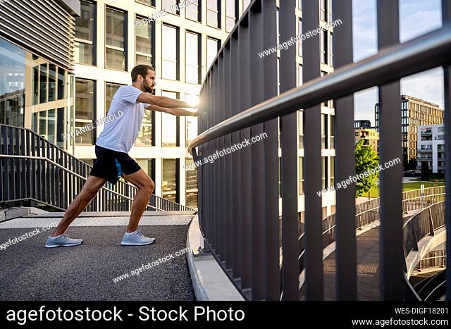 Young man doing warm up exercise on footbridge
