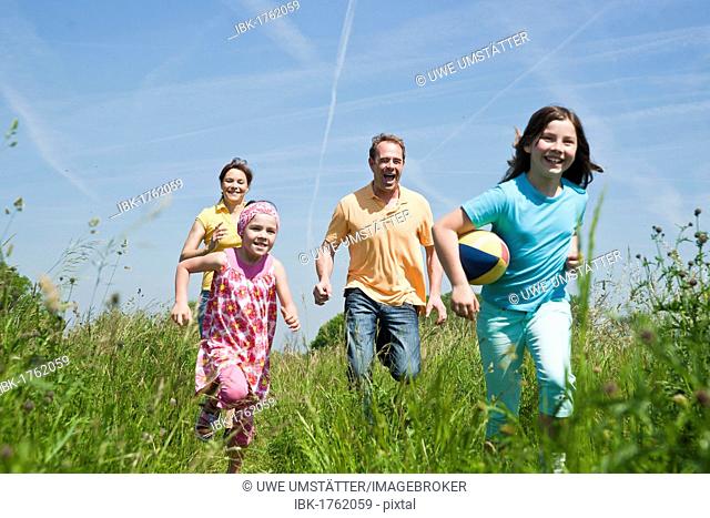 Family playing joyfully with a ball in a flower meadow
