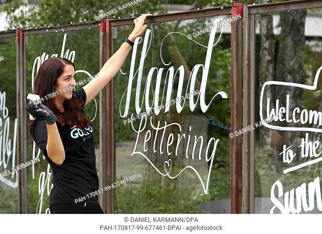 Nuremberg based artist and designer Hannah Rabenstein is painting on a window glass with white acrylic paint in Nuremberg, Germany, 10 August 2017