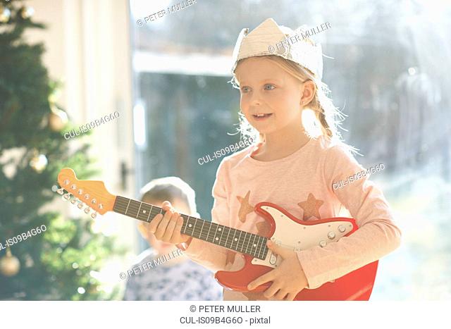 Girl playing with toy guitar on christmas day