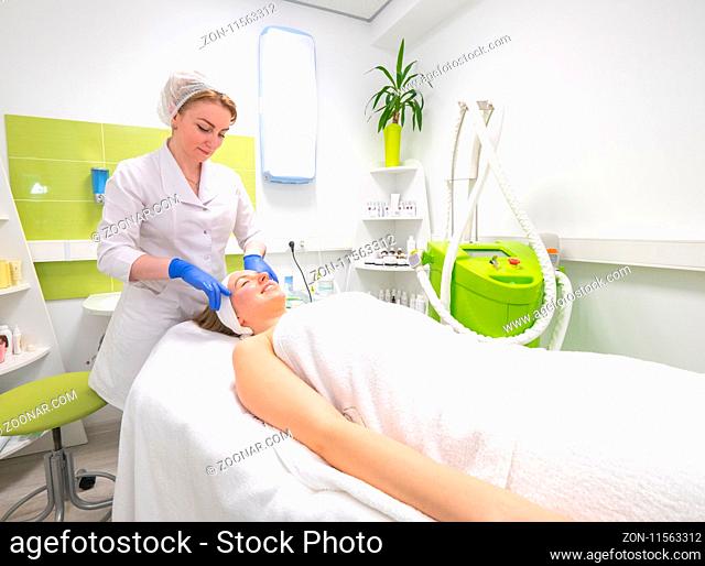 Doctor massaging patient's face. Model and doctor. Cosmetological clinic. Medical equipment. Healthcare, clinic, cosmetology