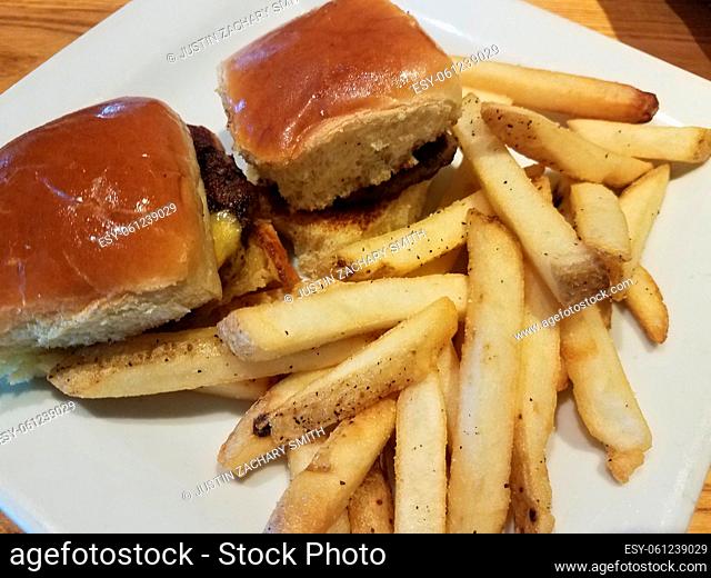 hamburgers with cheese on white plate with french fries