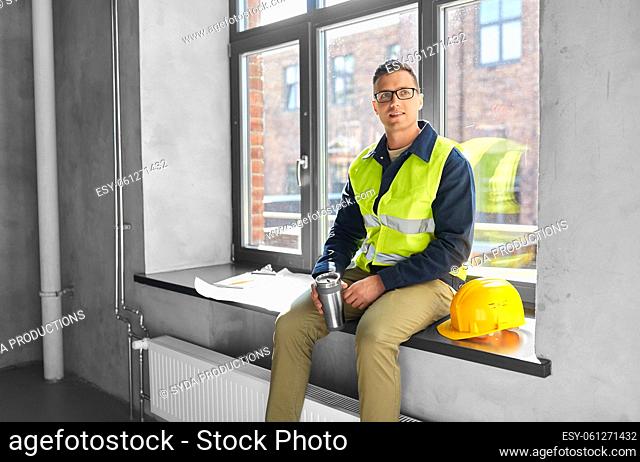 happy builder with tumbler sitting on window sill