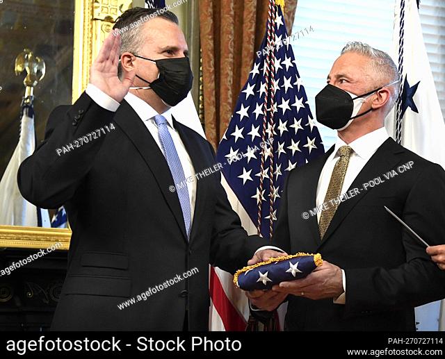 The State Department's Chief of Protocol Rufus Gifford (L) is sworn in as his husband Stephen DeVincent holds an American flag, by Vice President Kamala Harris