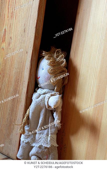 A rag doll is stuck in a wooden cabinet