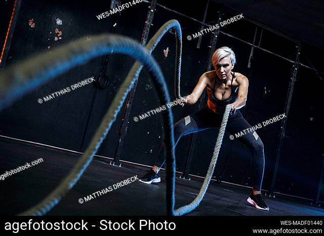 Blond sportswoman having workout with ropes