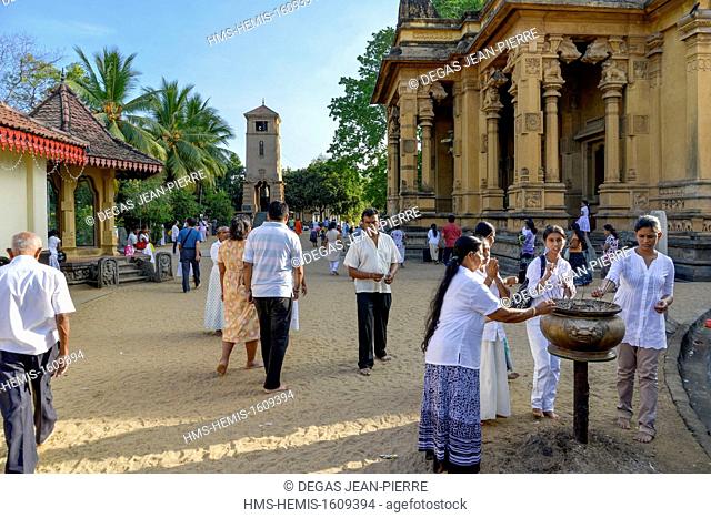 Sri Lanka, Western Province, Colombo District, Kelaniya, Kelaniya Raja Maha Vihara's Buddhist temple, pilgrims in front of a tub with incense with the temple of...