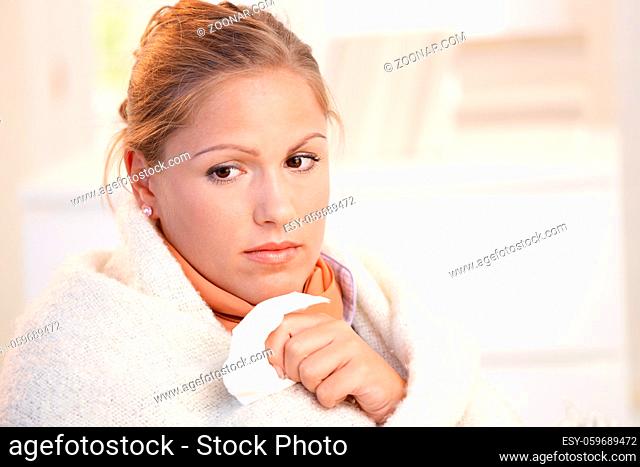 Young female having flu, feeling bad, wrapped up in blanket