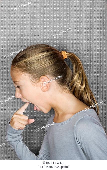 Studio portrait of girl 12-13 inserting finger in mouth