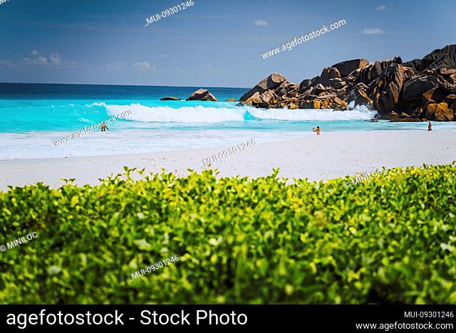 Unrecognizable tourist dabble in blue colored waves at Grand Anse beach, La Digue Island, Seychelles