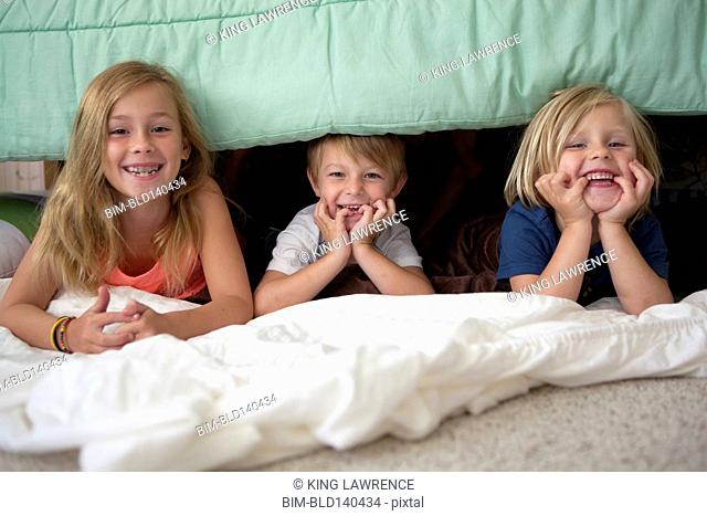 Caucasian children laying under bed