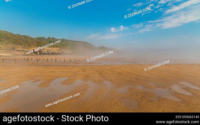 Wooden stakes on a foggy beach, seen at Sandsend Beach near Whitby, North Yorkshire, UK