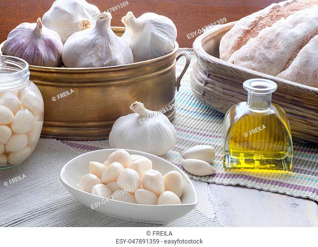Composition of garlic including whole cloves and pickled set in a kitchen on a wooden table, copy space bottom right
