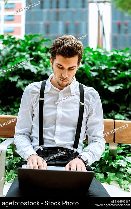 Young businessman working on laptop outdoors