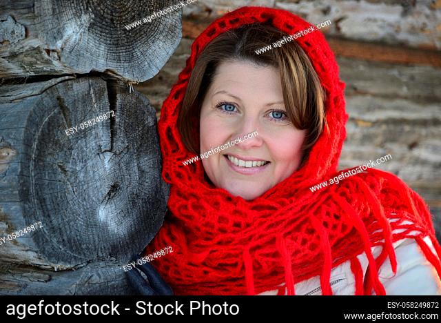 The Russian woman in a shawl warms hands near an izba