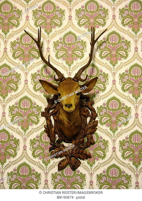 Plastic deer head on an old-fashioned wallpaper