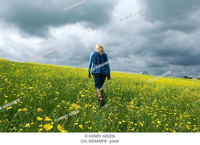 Woman walking in field of buttercups