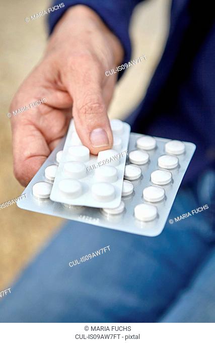 Womans hand holding blister packs of pills
