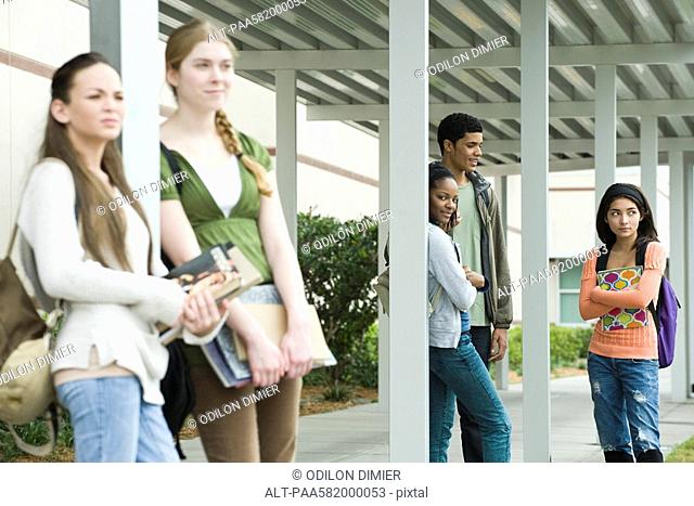 High school students waiting under covered walkway for bus after school