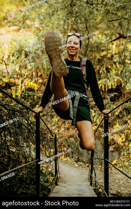 Smiling woman swinging on bridge railing at Sierra De Hornachuelos, Cordoba, Spain