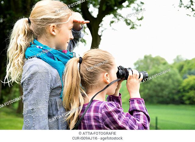 Two sisters using binoculars