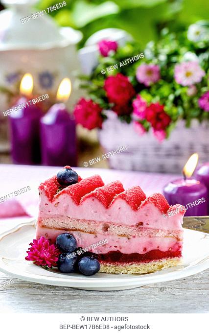 Pink layer cake decorated with fresh fruits on wooden table. Selective focus
