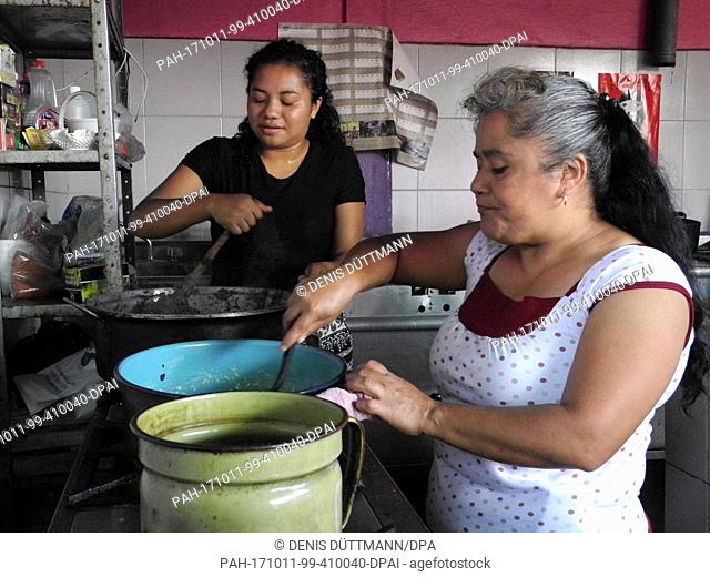 Julia Ramirez Roja (r) and a volunteer helper cooking beans and rice for migrants riding on the outside of freight trains, in Amatlan de los Reyes, Mexico