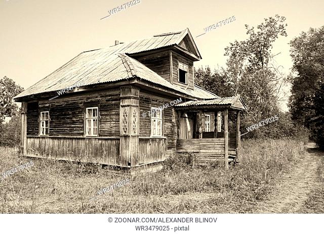 Retro photo with old wooden broken house in russian abandoned village in summer day