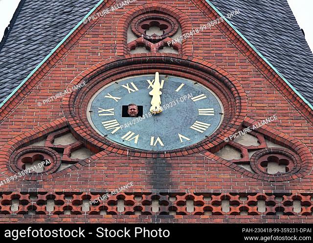18 April 2023, Brandenburg, Frankfurt (Oder): Holger Bittner from the company Bittner Glocken- und Turmuhren looks out of an opening in the southern tower clock...