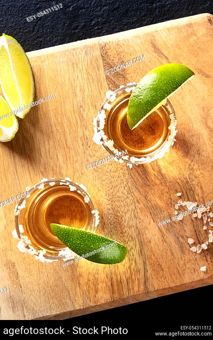 Golden tequila shots with salt rims and lime slices, overhead close-up shot