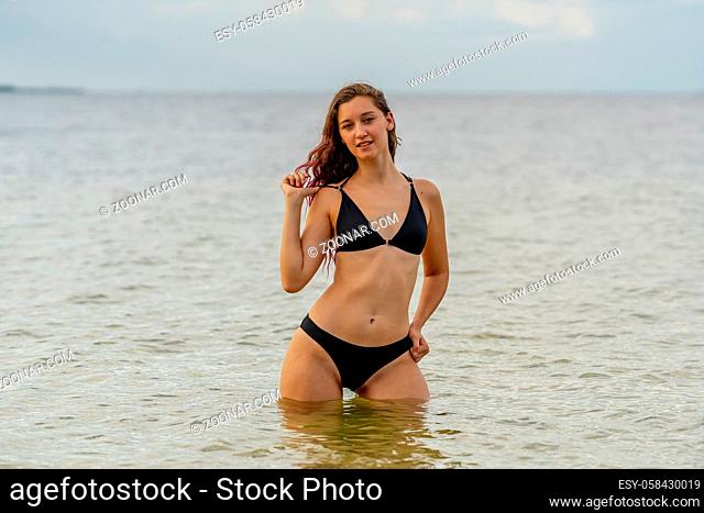 A beautiful Brunette bikini model enjoys the weather outdoors on the beach