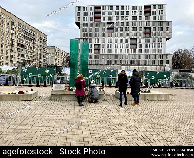 21 November 2023, Latvia, Riga: People lay flowers at the memorial for the victims of the Riga collapse tragedy. Ten years after the collapse of a supermarket...