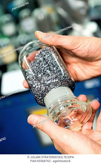 A man holds up a sample of the rare metal tungsten are displayed in the procedural center of the H.C. Starck chemical company in Goslar,  Germany