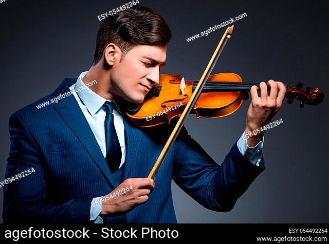 The young man playing violin in dark room