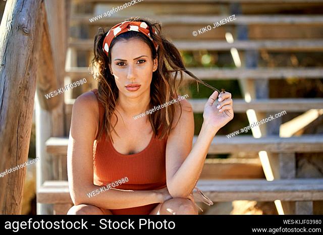Beautiful woman with hand in hair sitting on steps at beach